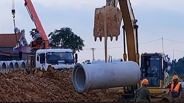 Máy xúc lắp đặt ống cống thoát nước.