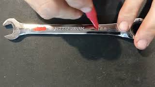 Painting the size markings on a chrome wrench.