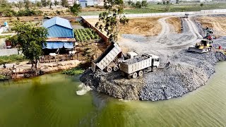 N.8: Dump Trucks Keep Dumping Stones Drop Into The Water To Compact The Land With Bulldozer
