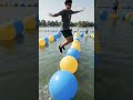 Deaf vlog-style video of me leaping across blue and yellow inflatable balls on a lake obstacle cours