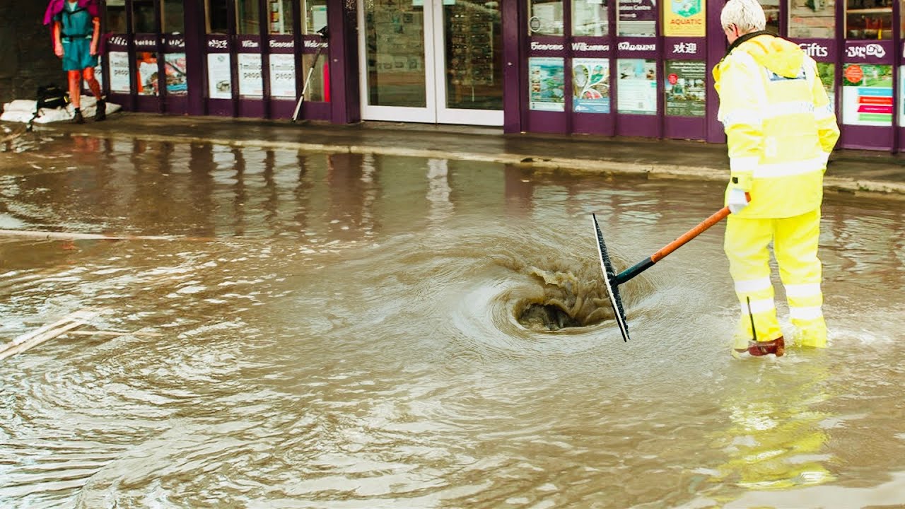 Flood Fighter Unclogging a Flooded Street Drain to Reopen the Road ...