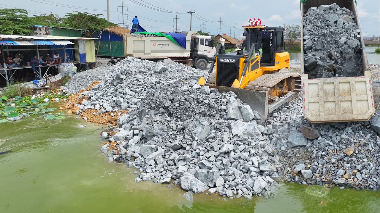 Good Work!!SHANTUI Bulldozer Pushing Stone Into Water With DONGFENG Dump Trucks Unloading Stone