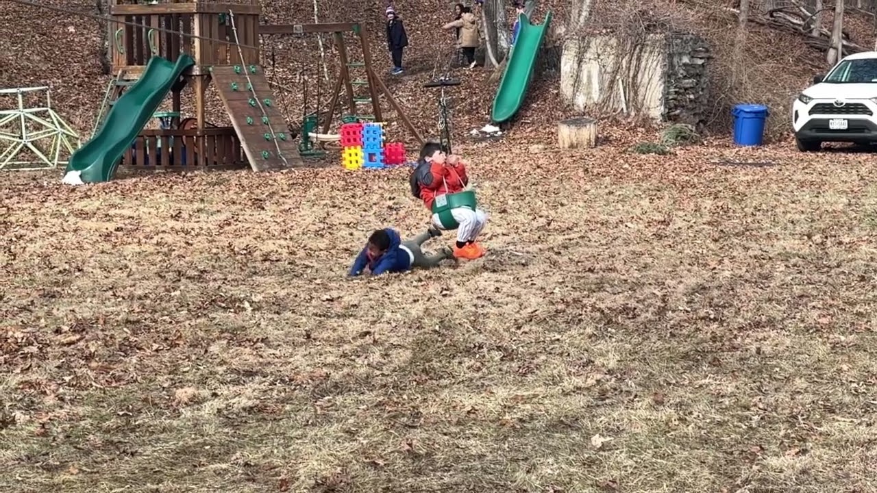 Boy in red rides on swing seated zipline and crashes into another kid Slow motion