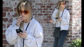 Kaley Cuoco enjoys a smoke break while scrolling through her phone on the Los Angeles set of the sec