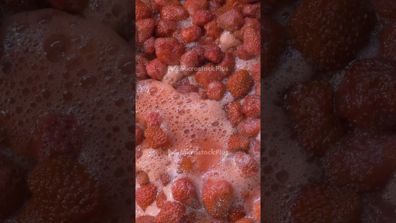 Strawberries are cooked in a large vessel, emitting steam as they boil