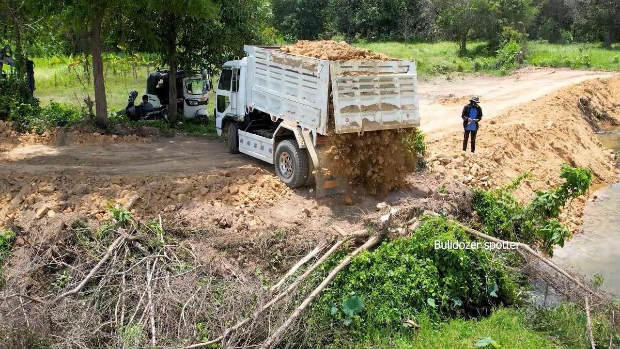 Be careful !! Dump truck unloading soil landfilling repair road with bulldozer working push soil 