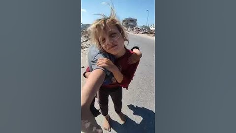 Палестинская девочка пытается спасти свою раненую сестру в секторе Газа, неся ее на руках более часа