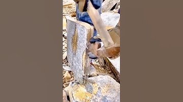 Worker splitting natural stone slabs using hammer and wedge technique