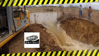 Busting the dam on a pond in preparation for demo with the 120 excavator