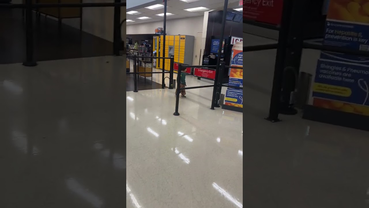 Little boy in sunglasses stands in front of automatic gate that opens and pushes him down