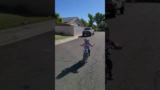 Boy on dirt bike hits gutter then helmet falls off and he lands on his stomach