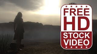 Free Stock Videos – woman standing on desert road looking at sunset with dust particles wind