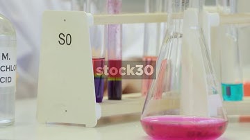 Scientist Swirling Coloured Liquid In Conical Flask