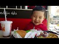 Sweet baby boy eating hamburger with ketchup, fries and juice in Burger King fast food restaurant.