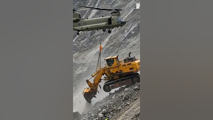 An Excavator Machine Has Fallen Down A Mountain And Is Being Taken Wway By A Chinook Helicopter.
