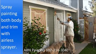 Painting the exterior of a house with spray gun.