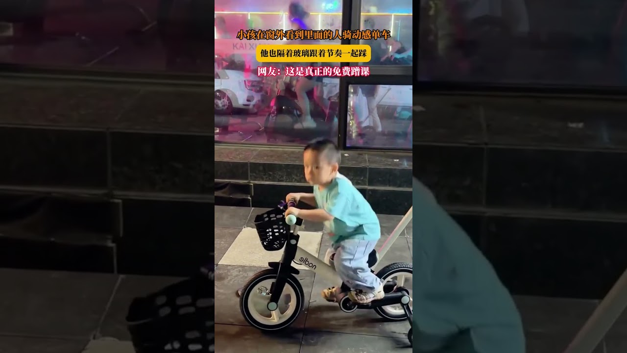 小孩在窗外看到里面的人骑动感单车，他也隔着玻璃跟着节奏一起踩，网友：这是真正的免费蹭课