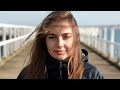 Hot Brunette Woman With Long Hair Wearing a Windbreaker Coat Waits in Very Strong Storm Winds