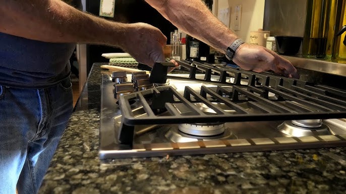 A person's hands placing a grate on a gas stove after a professional installation, showing who installs gas cooktops properly