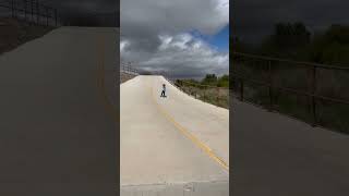 Boy rides scooter downhill then speed wobbles and rolls on the ground