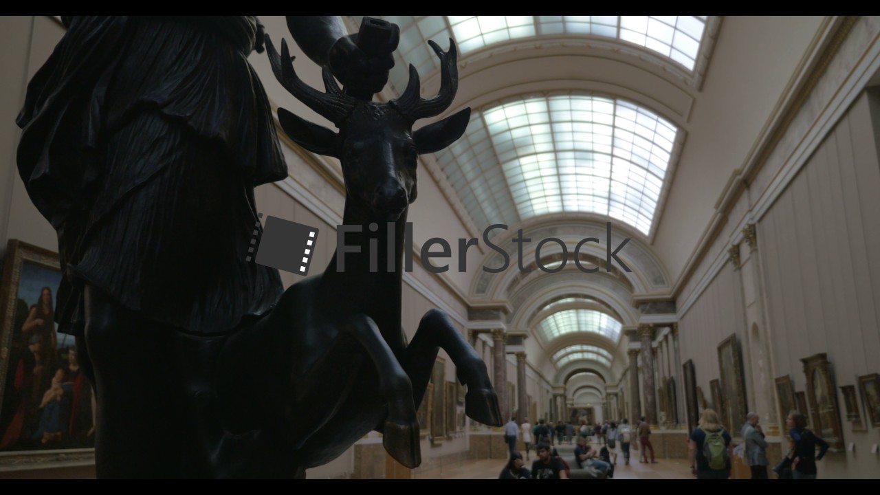 Visitors in the Louvre hall with paintings and sculptures