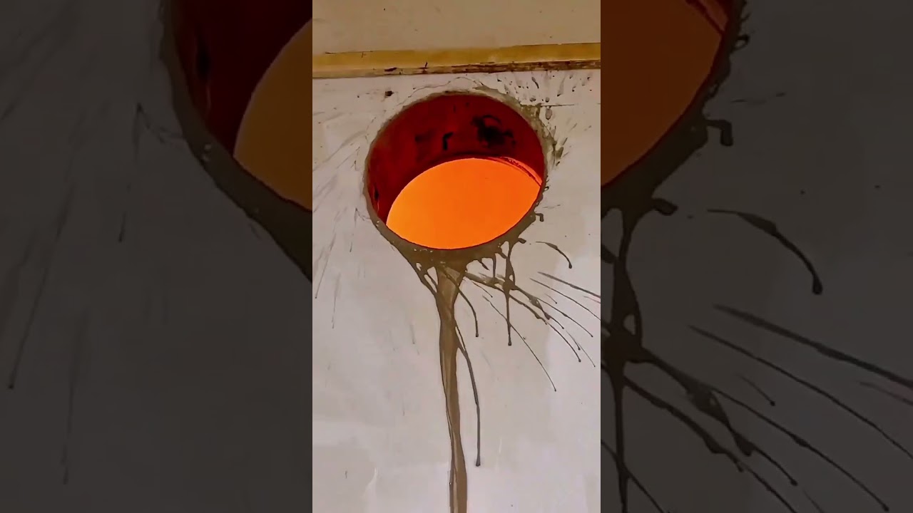 Construction Worker on a Ladder, Wearing a Yellow Hard Hat, Drilling a Large Hole in a Ceiling