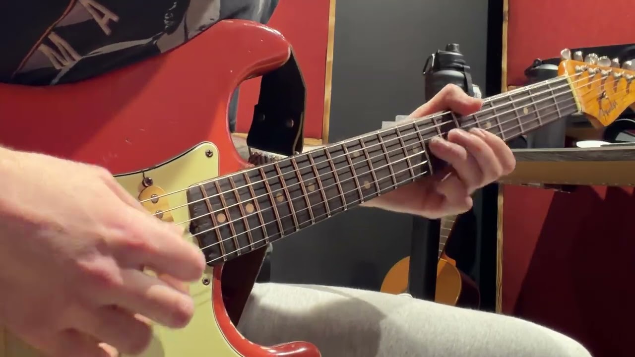 Возится с гитарой Stratocaster цвета Fiesta Red 1963 года выпуска.