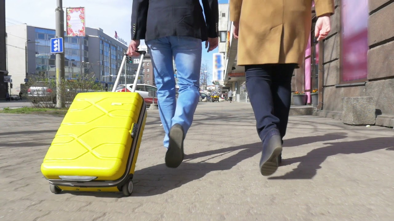 Slow motion steadicam shot of a couple walking along the street back to the camera man rolling trave