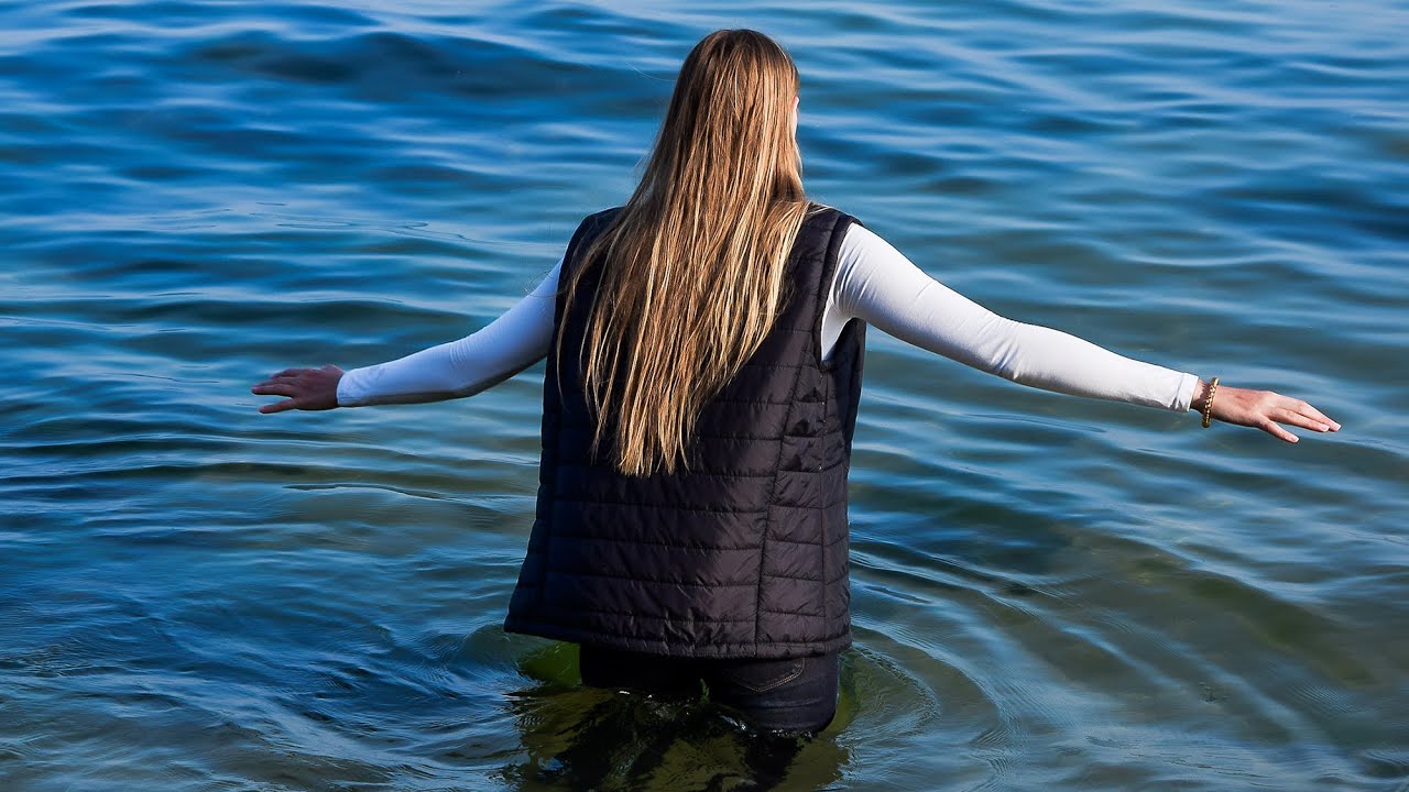 DON'T MISS! PRETTY GIRL IN WARM WET CLOTHES POSES TENDERLY ON THE BEACH BY THE SEA FOR WETLOOK VIDEO