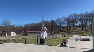 Woman on roller skates rides up quarter pipe at skatepark then falls and bumps nose on spine of ramp