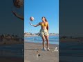 فتاه تعمل مهارات بالكرة على الشاطئ 