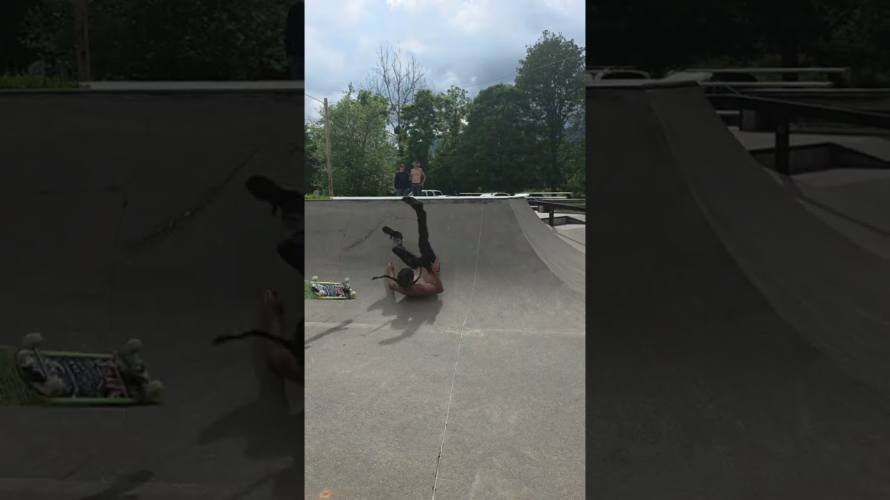 Skateboarder attempts handplant on ramp at skatepark and lands on his back