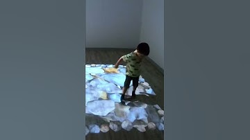 Kid searches for dinosaur bones on an interactive projector rock floor