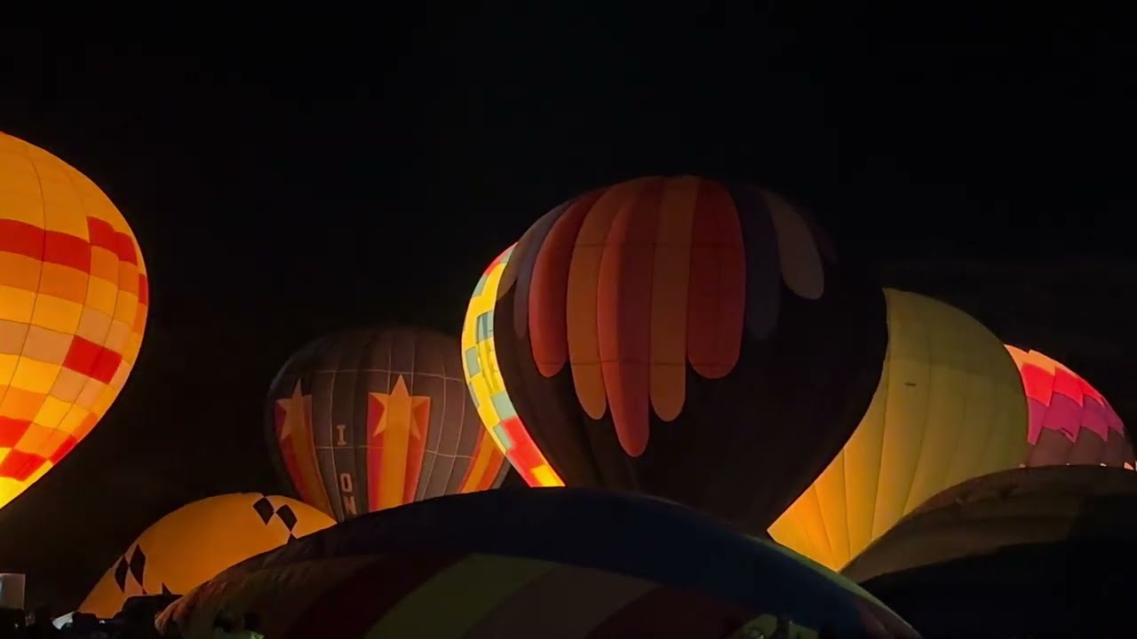 Group of hot air balloons lighting up during the balloon glow