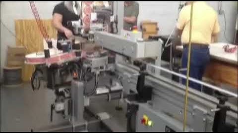 Label Applicator applies label to the top and side of a plastic container