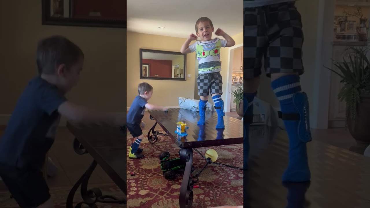 Boy in Buzz Lightyear shirt attempts to jump off coffee table onto couch and falls on the floor