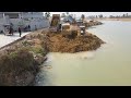 Bulldozer d31p work push soil and dump truck moving soil into water continue build resize road