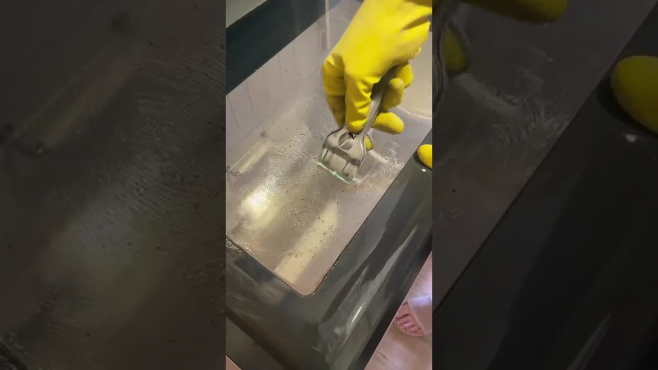 Limpiando con guantes el cristal de un horno en Madrid
