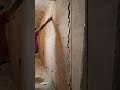 Painter leveling gypsum and scraping off large white spots