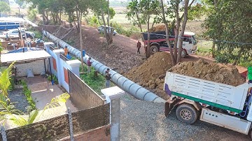 Processing Dump truck and bulldozer push soil bury long sewer drainage system next to the home