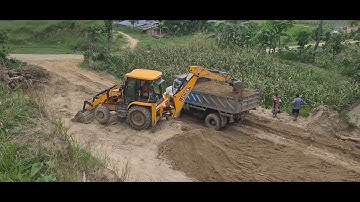 Jcb Backhoe machine loading soil in truck and leveling hill land