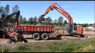 Hitachi Zaxis 225 US with OilQuick loading JCB Fastrac 3200 with Bigab Hooklift trailer