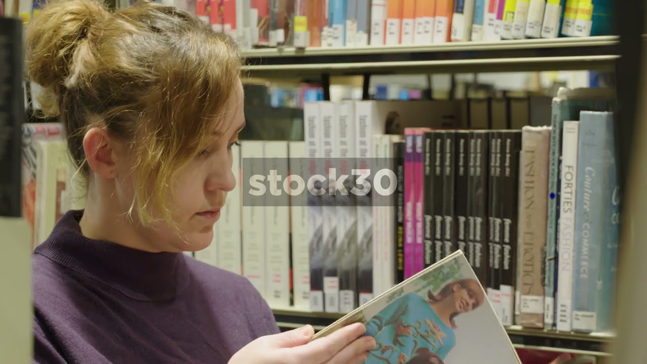 Woman In Library Contemplating And Looking Through Books