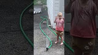 Little girl accidentally sprays herself on her face with garden home in backyard