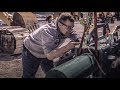 A heavy equipment mechanic uses a portable 100ton track press for excavator pins