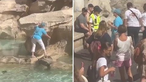 Una turista riempie la bottiglia con l'acqua della fontana di Trevi, a Roma