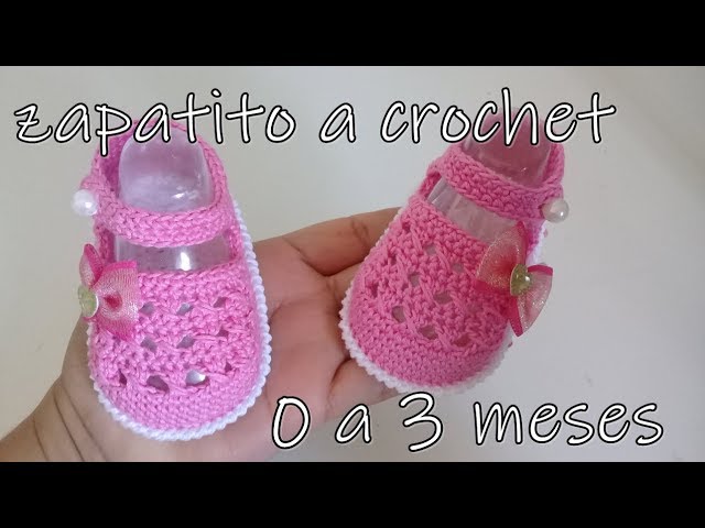 Zapatitos de bebé. zapatillas tejidas a mano para recién nacido niño o niña  en la pared gris.