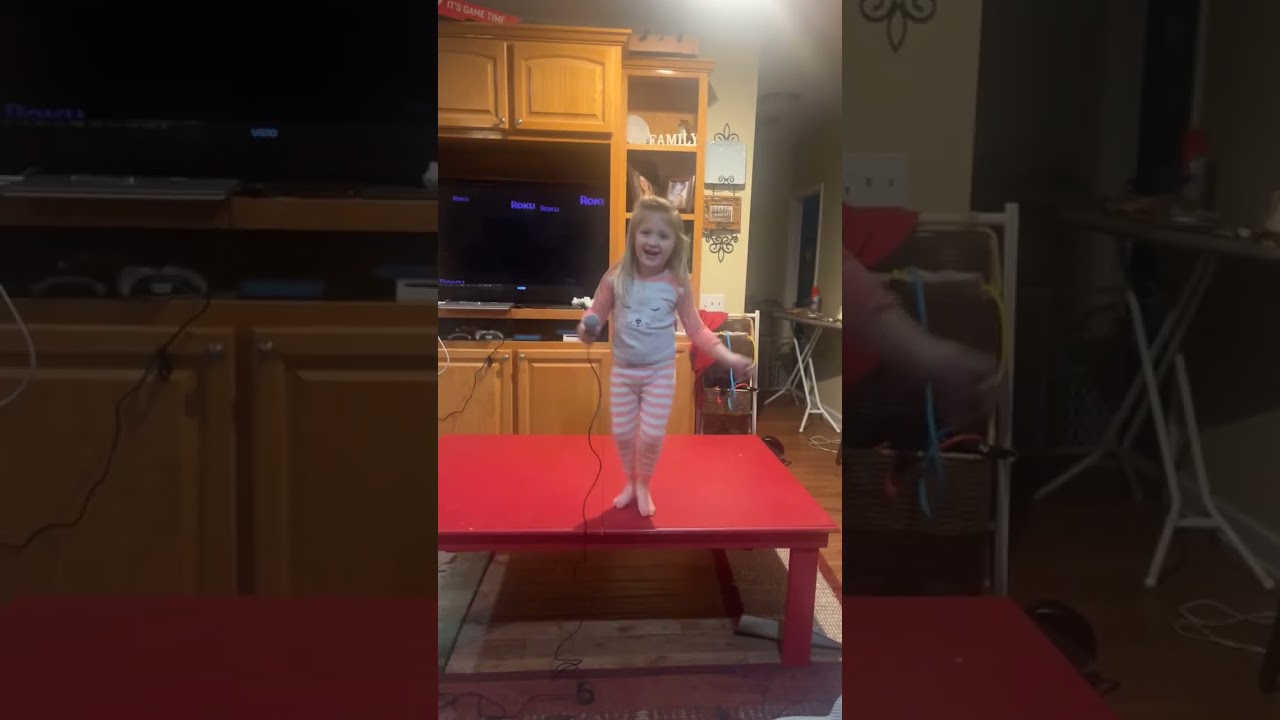 Girl holding microphone dances on table to What does the fox say then falls on floor in living room