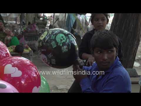 Balloon seller prepares balloons for children in a Delhi village