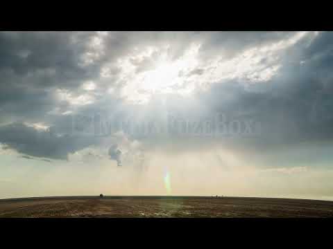 Stock Video - Time lapse of sun rays shining through the clouds moving over flat landscape
